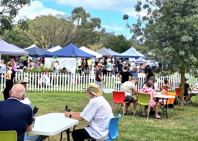 South Canberra Community Markets wide-angle view of stalls with people relaxing and looking around. 