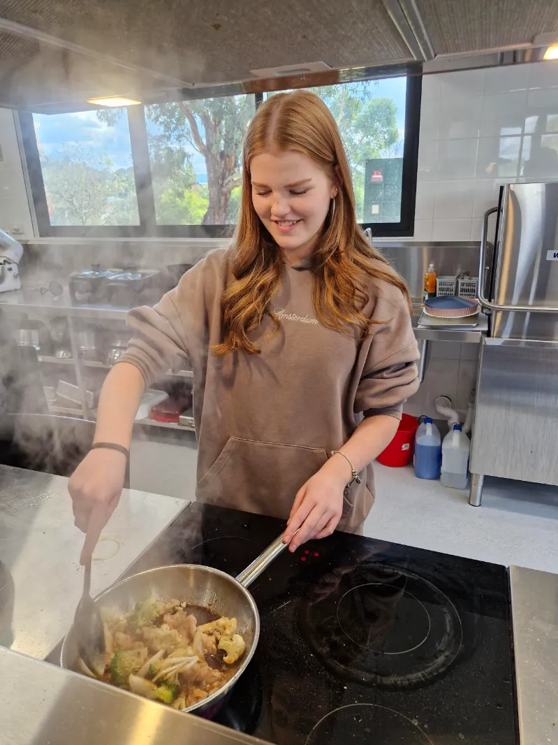 A Galilee student cooking on a stove. 