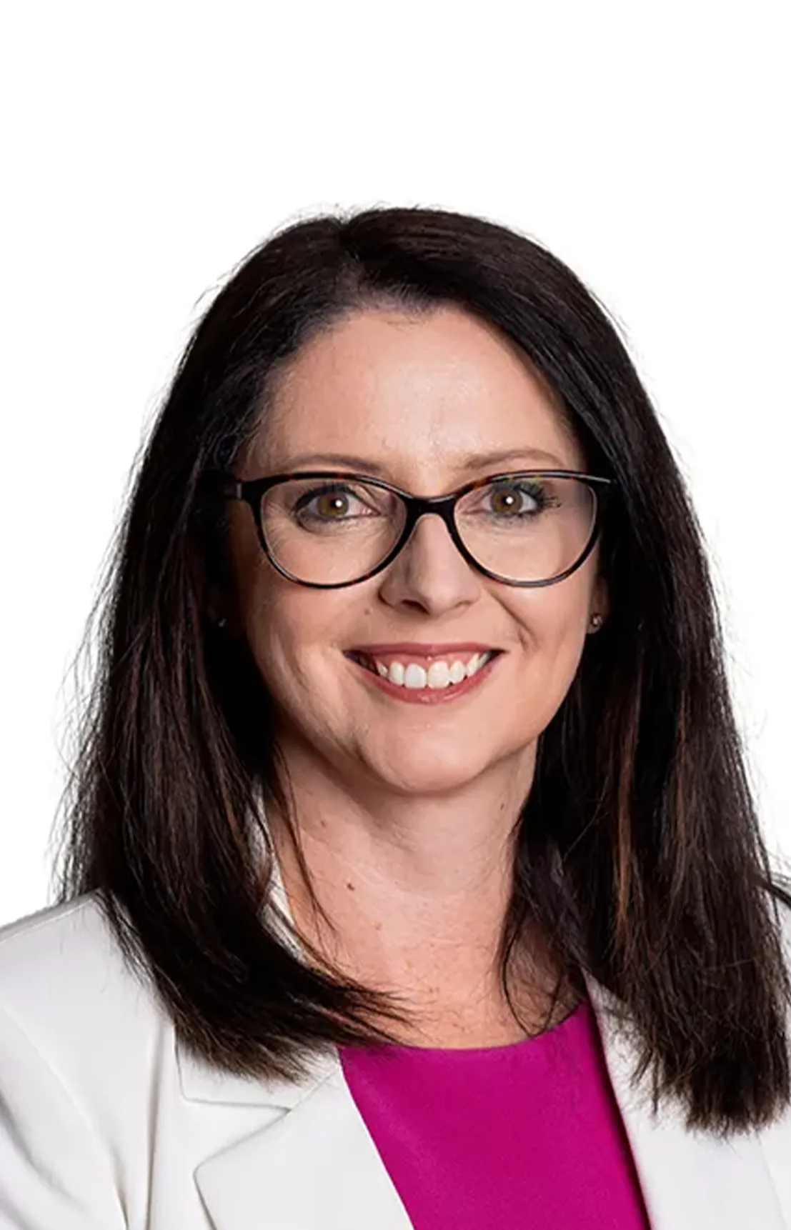 A woman with glasses wearing a pink shirt with a white jacket smiling.
