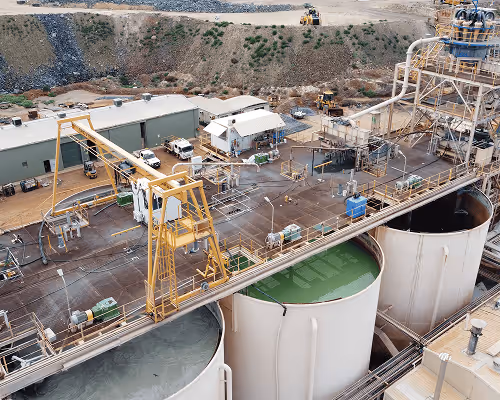 Aerial view of an industrial site with large cylindrical storage tanks, metal structures, and machinery.