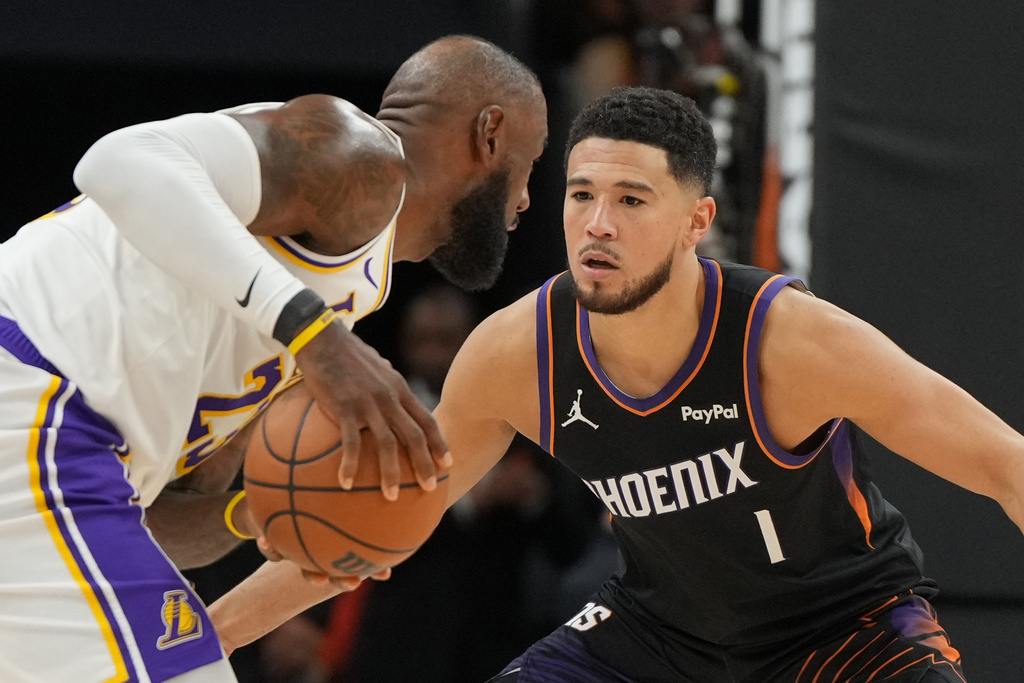 Suns G Devin Booker guards Lakers F LeBron James in an NBA game.