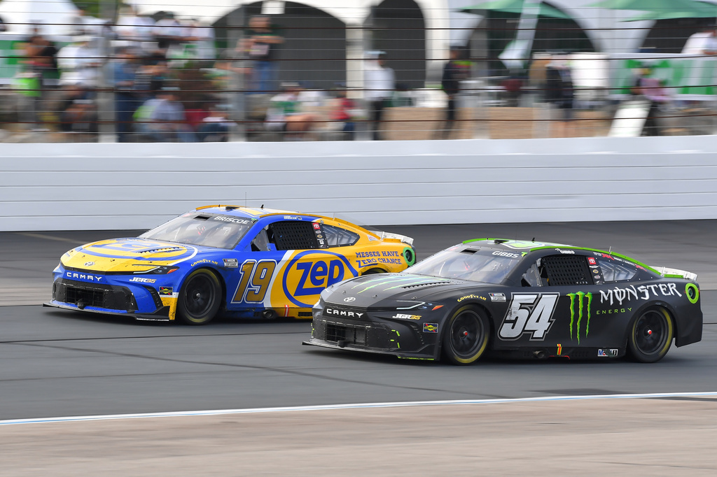 Chase Briscoe and Ty Gibbs steer their cars out of turn four during a NASCAR Cup Series race.