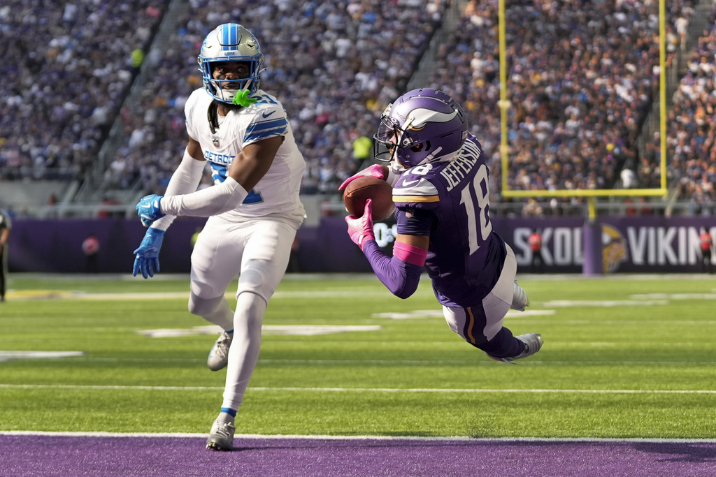 Minnesota Vikings wide receiver Justin Jefferson (18) catches 25-yard touchdown pass as Detroit Lions cornerback Amik Robertson (21) defends during the second half of an NFL football game.