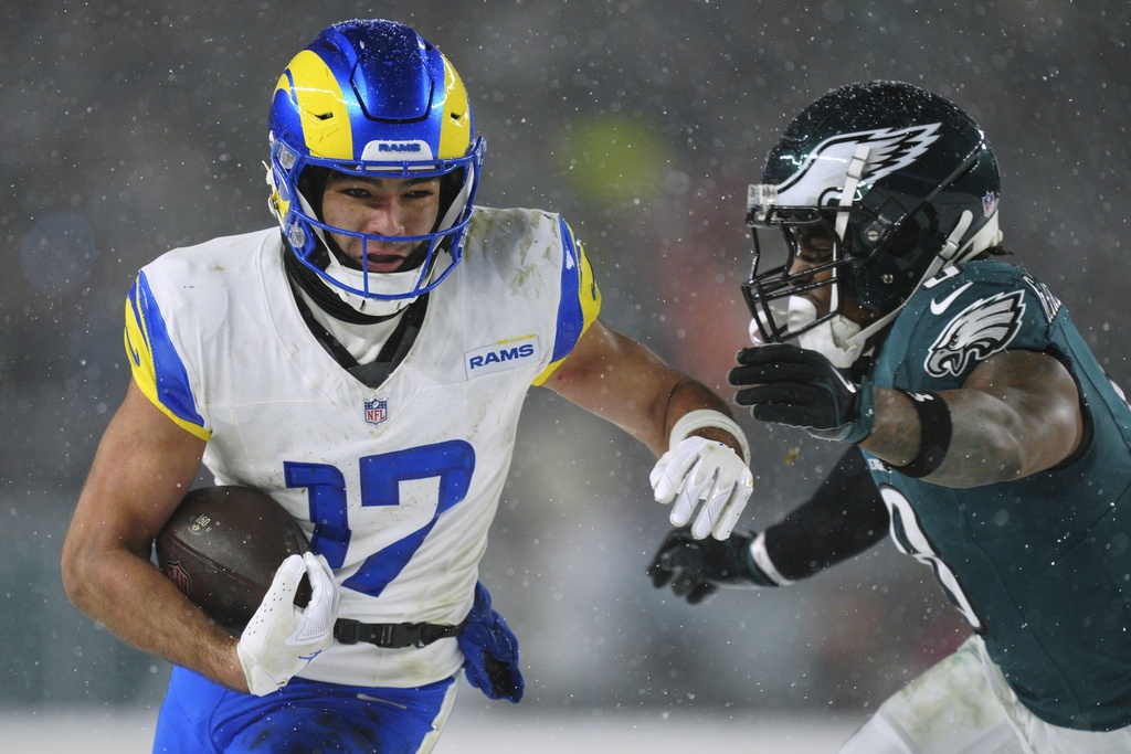 Rams WR Puka Nacua carries the ball with an Eagles defender in pursuit during the 2025 playoffs.