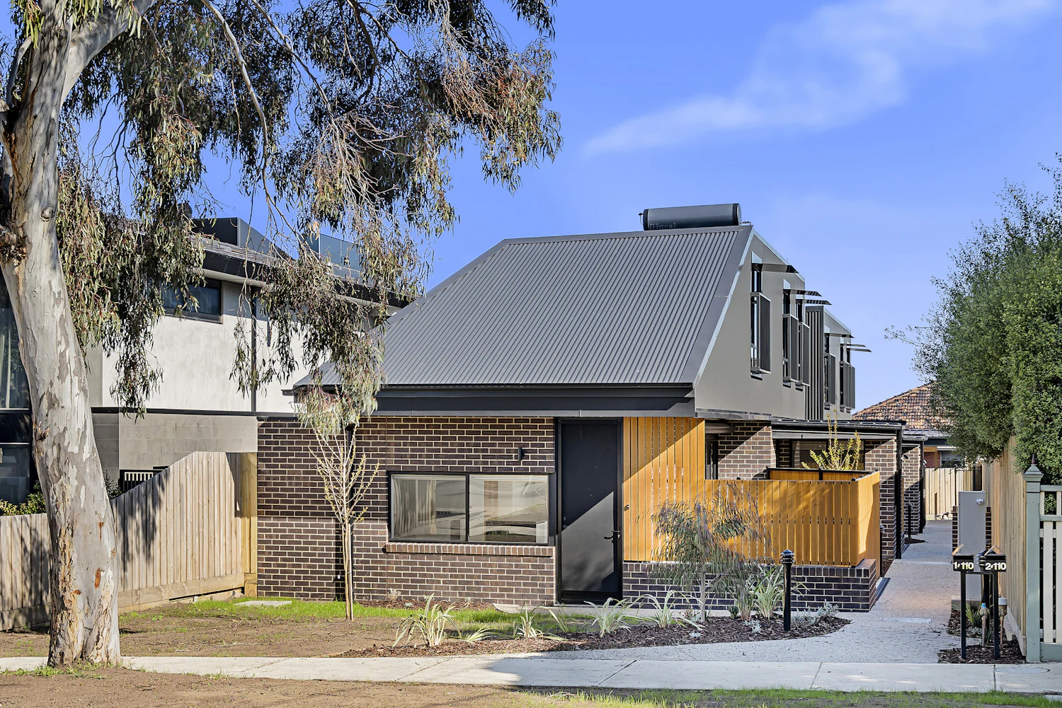 Single-storey brick and timber unit with a landscaped front garden and gum tree, built by Harnest