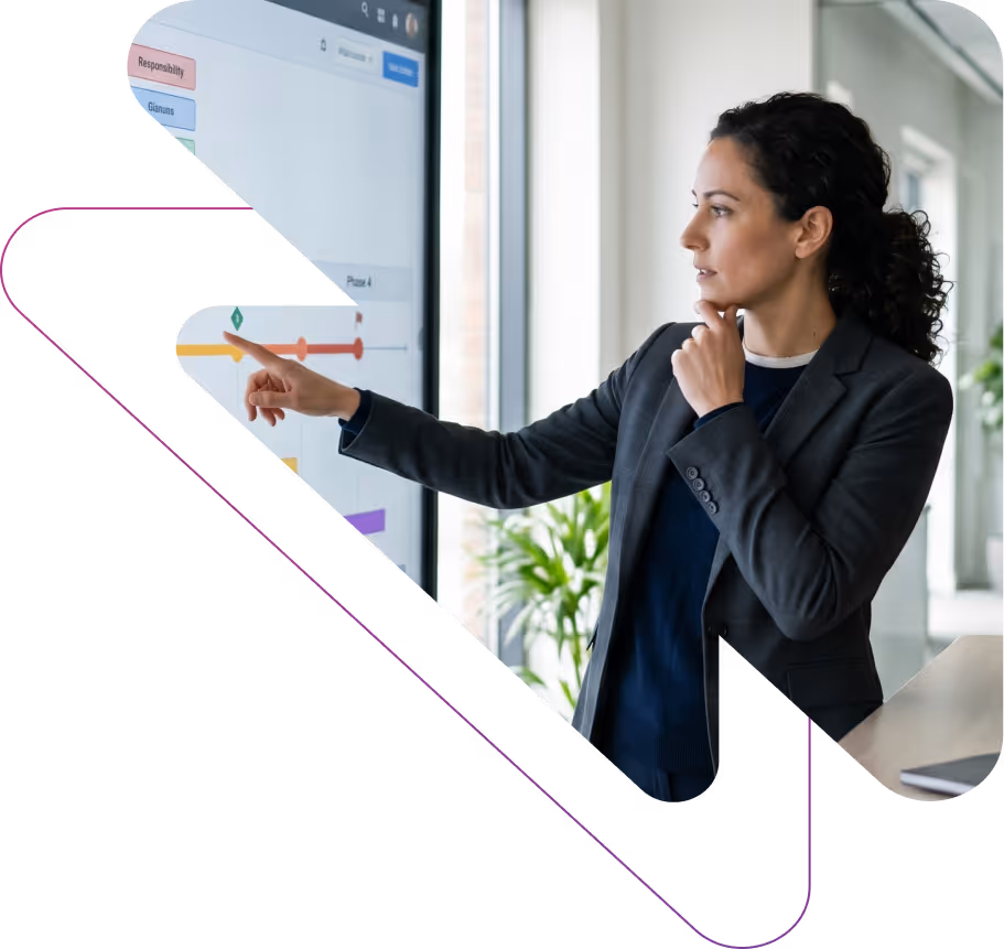 Businesswoman in a suit analyzing data on a touchscreen monitor in a modern office.