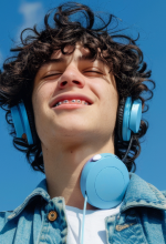 Green robotic vacuum cleaner operating on wooden floor in a bright living room with a sofa and glass coffee table.