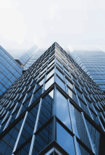 Person using a vacuum cleaner to clean office carpet near desks and chairs.