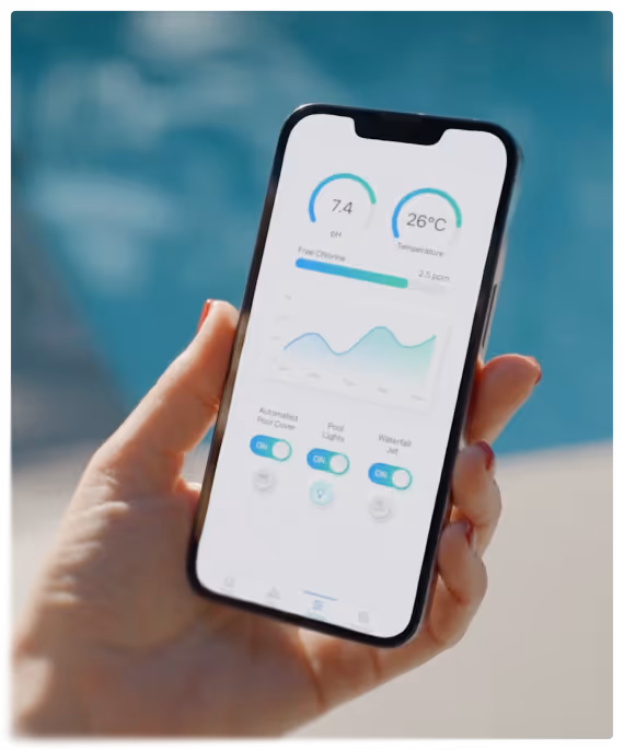 Personne tenant un smartphone affichant une application de surveillance de piscine avec des indicateurs de pH à 7,4 et de température à 26 degrés Celsius.