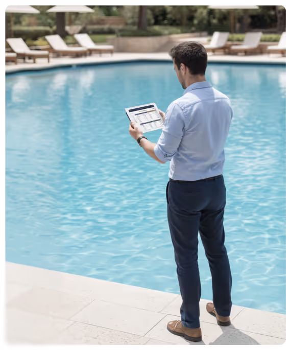 Homme en tenue professionnelle debout au bord d'une piscine, tenant une tablette avec un tableau financier à l'écran.