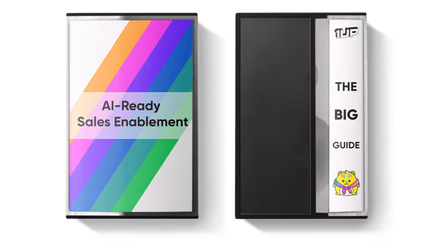 Two VHS tape cases side by side, one with a colorful diagonal stripe design reading 'AI-Ready Sales Enablement' and the other labeled 'The Big Guide' with a small cartoon character on the spine.