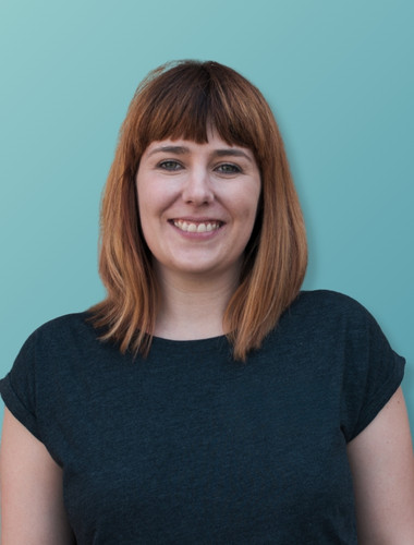 Porträt einer lächelnden Frau mit schulterlangem braunem Haar und Pony vor einem hellblauen Hintergrund.