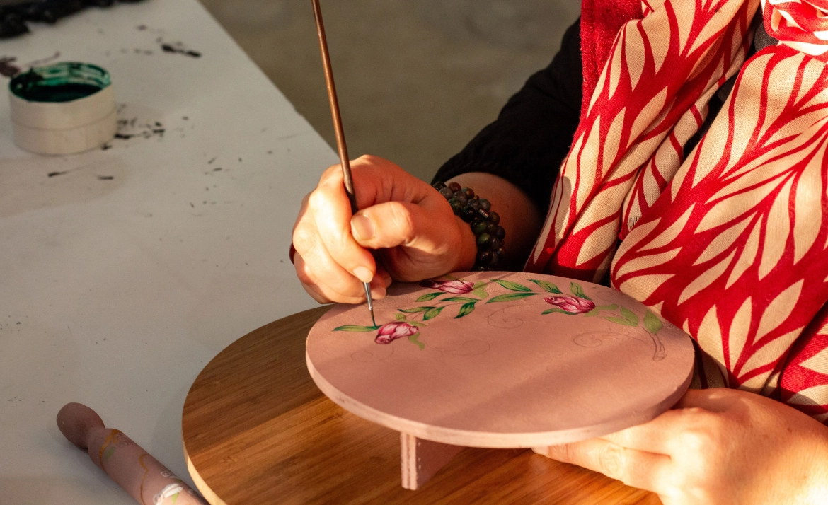 Hand malt mit Pinsel Blumenmuster auf runden Holzuntersetzer