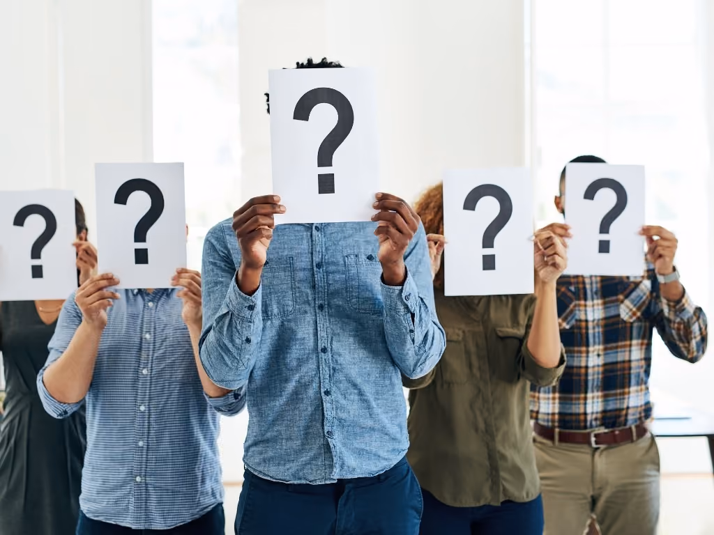 A group of people holding question mark cards in front of their face.