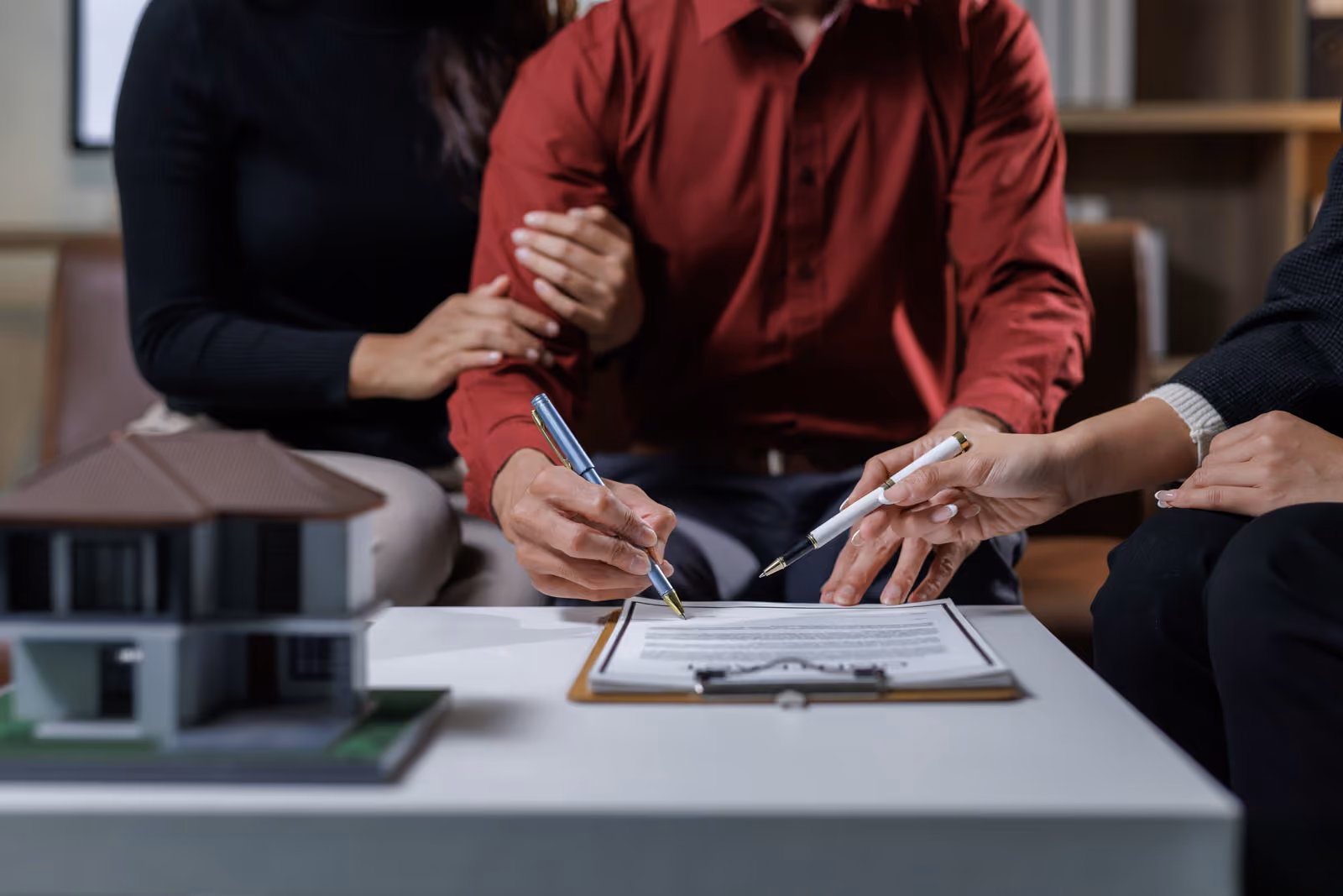 Couple signing estate planning documents with advisor at table