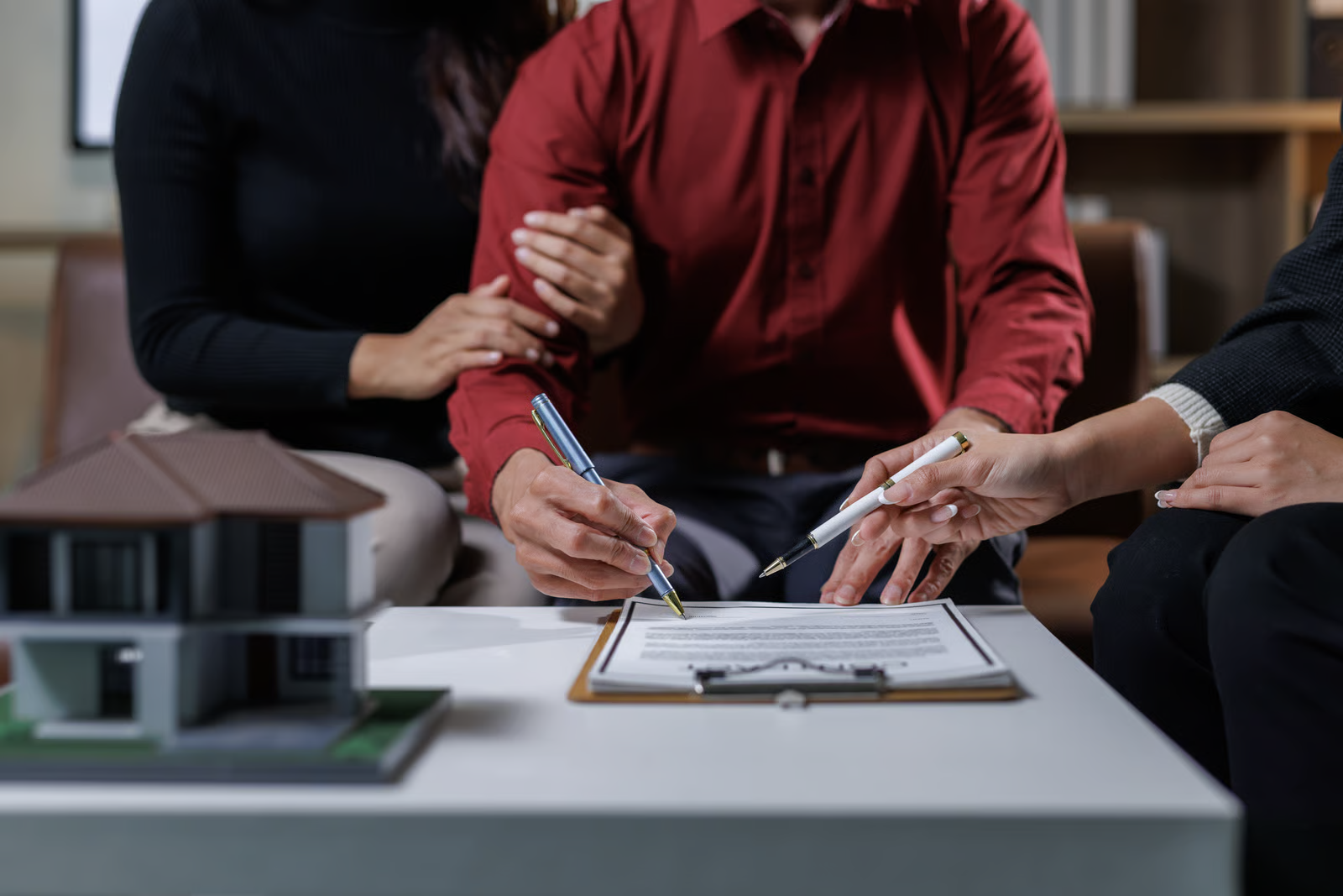 Couple signing estate planning documents with advisor at table