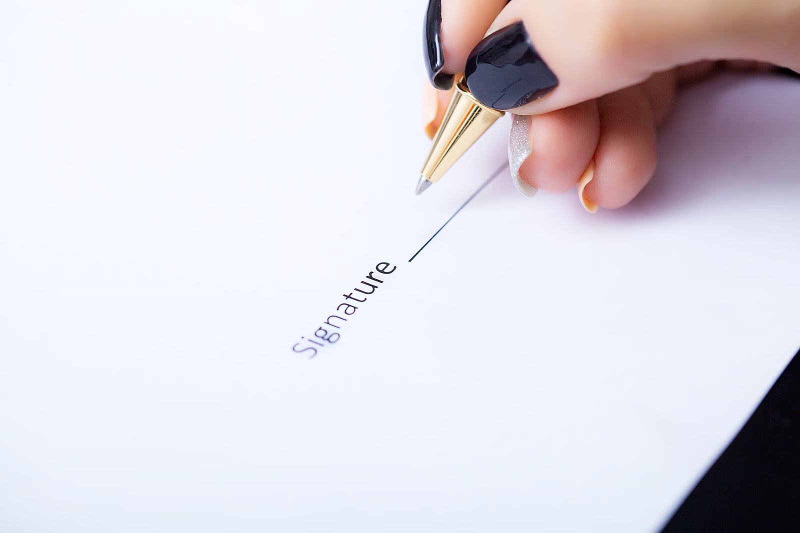 Close-up of hand signing a document, representing legal authorization and estate planning