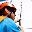 Construction worker in safety gear holding a measuring rod at a building site.