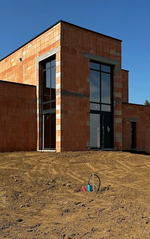 Maison en briques en cours de construction avec grandes fenêtres