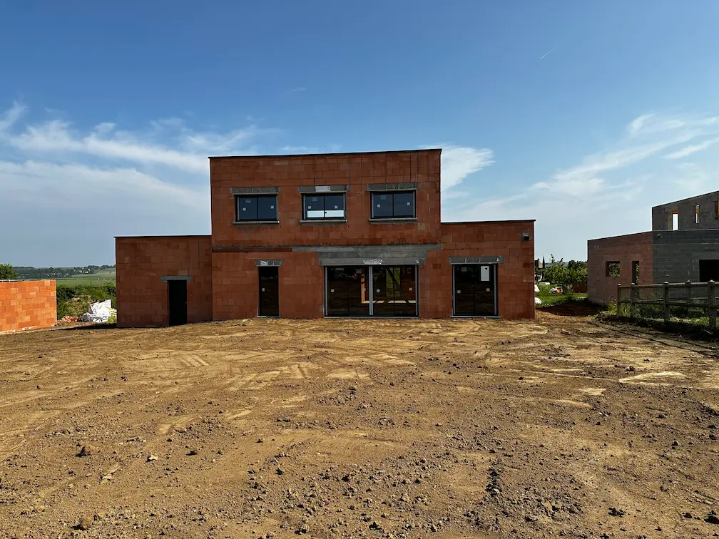 Maison en construction avec murs en parpaings et charpente en cours de pose