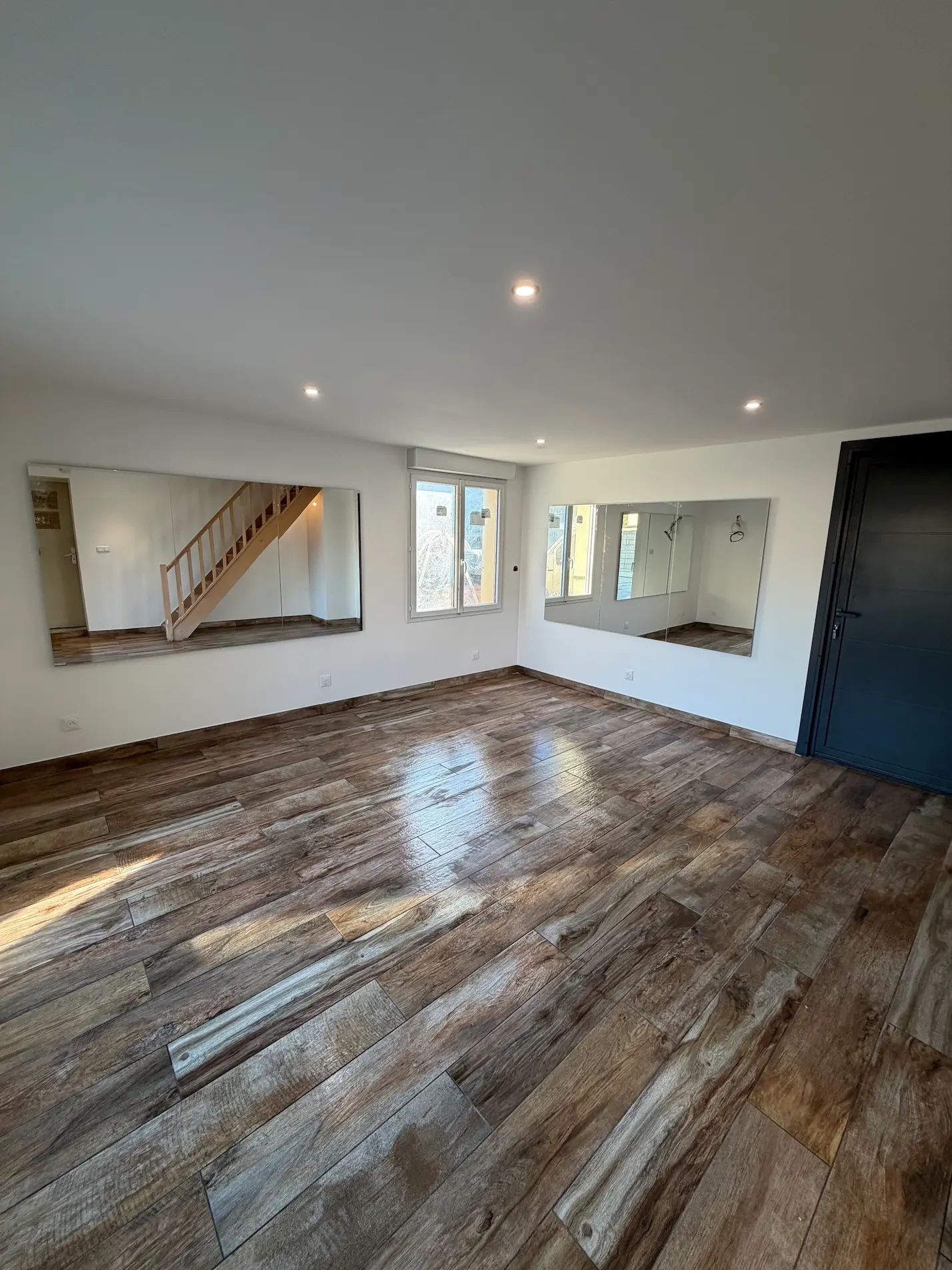 Pièce de vie rénovée avec escalier en bois, baie vitrée coulissante et carrelage imitation bois