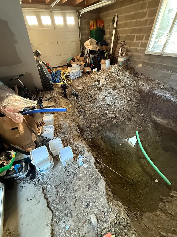 Garage en cours de travaux avec tranchée creusée pour passage de canalisations