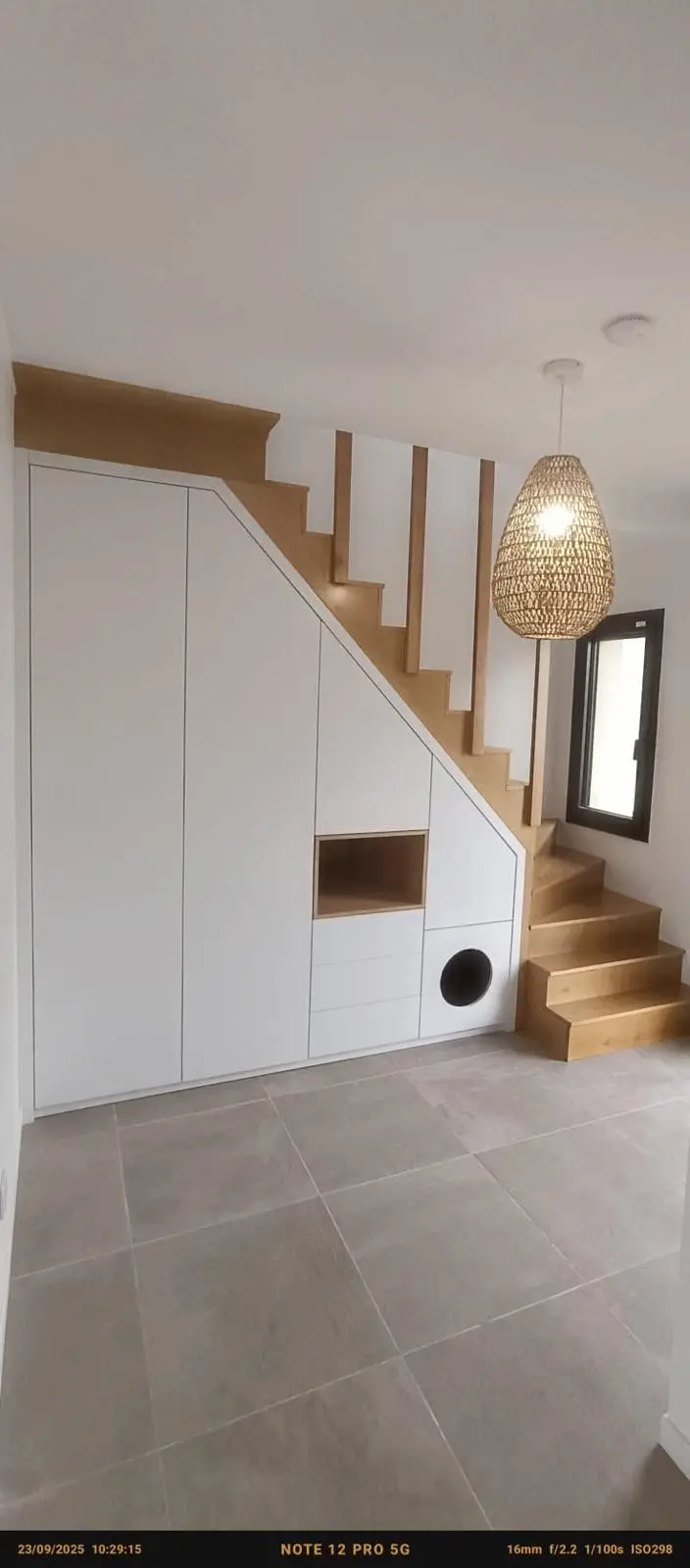 Pièce intérieure avec escalier blanc et carrelage gris clair, finitions en cours