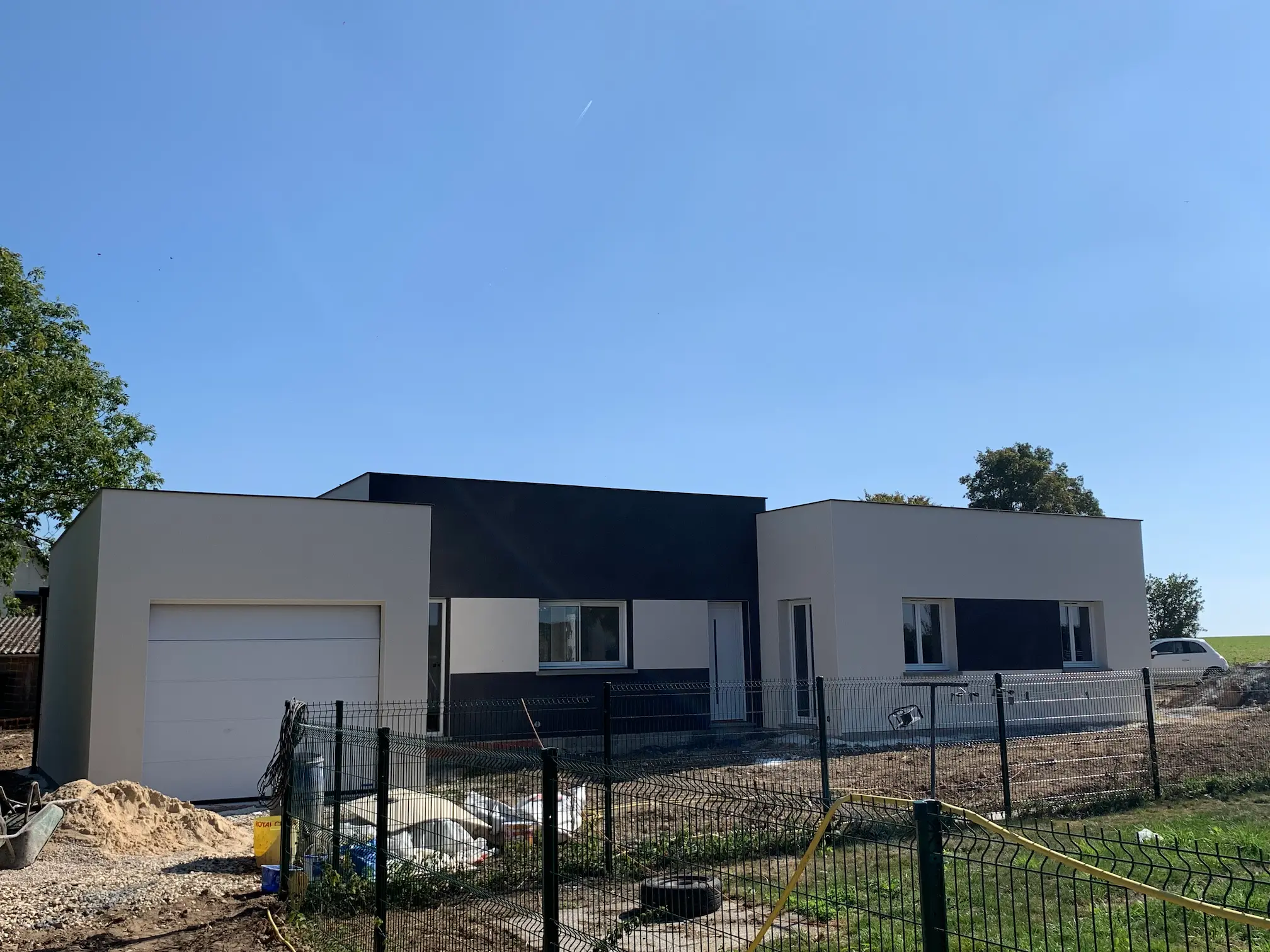 Maison contemporaine terminée avec façade blanche, toit plat et aménagement extérieur