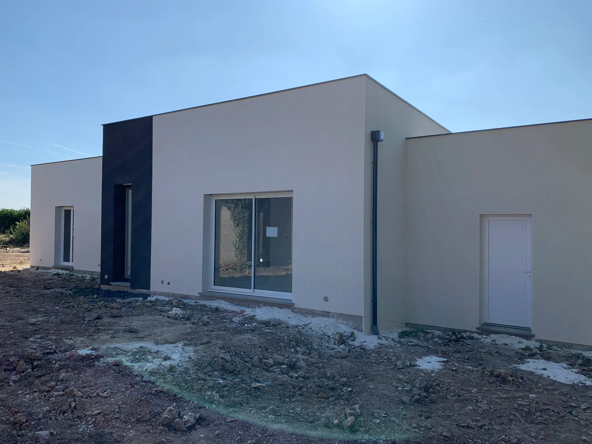 Maison contemporaine avec façade enduite blanche et toit plat, finitions extérieures en cours