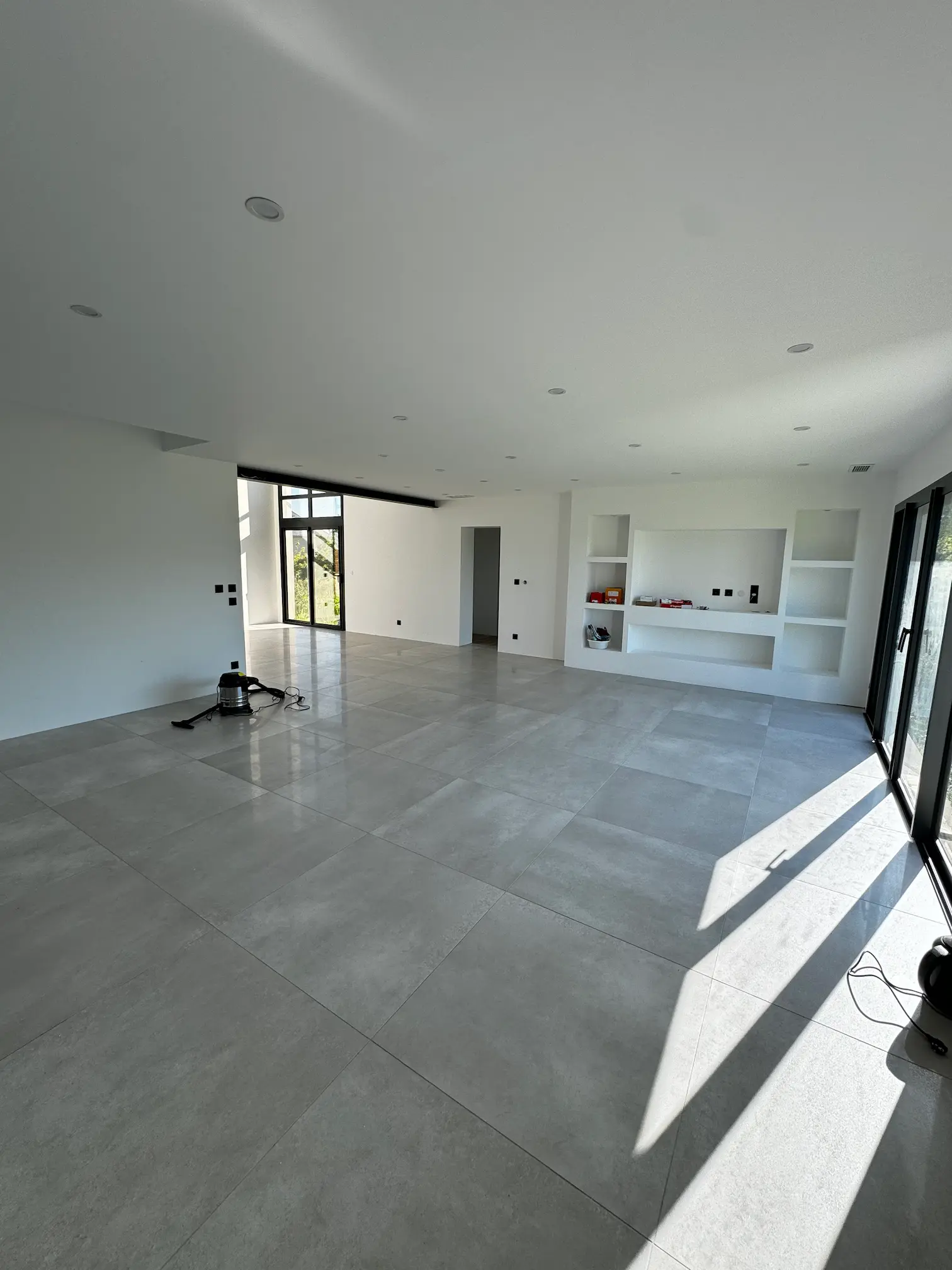 Espace intérieur lumineux avec cuisine ouverte, carrelage clair et finitions blanches