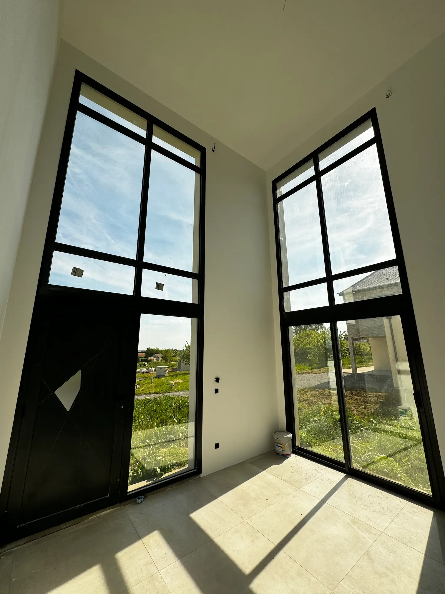 Intérieur avec double hauteur et baies vitrées grand format apportant une lumière naturelle abondante