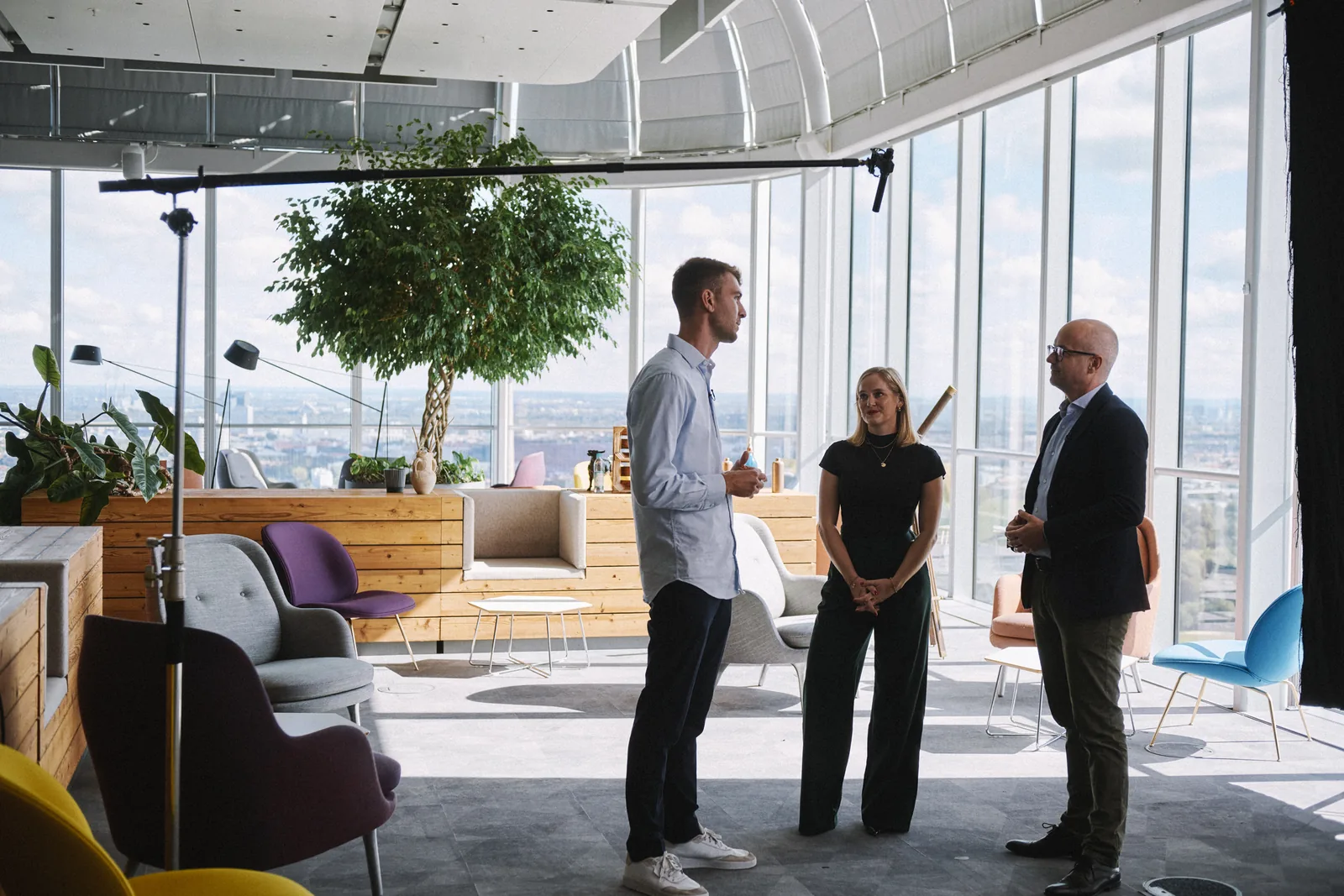 Drei Kolleginnen und Kollegen im Gespräch in der Wayra-Lounge mit Blick über München