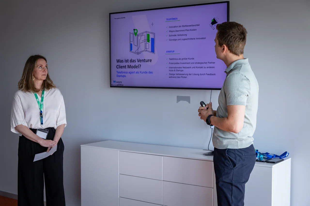 Two people presenting the venture client model in front of a screen in the office