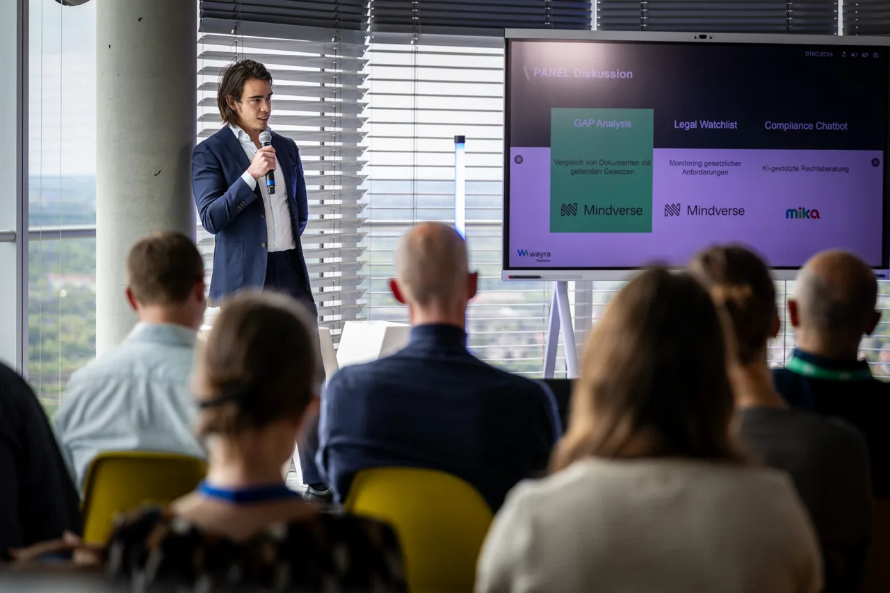 Speaker mit Mikrofon präsentiert vor Publikum in einem Wayra-Workshop