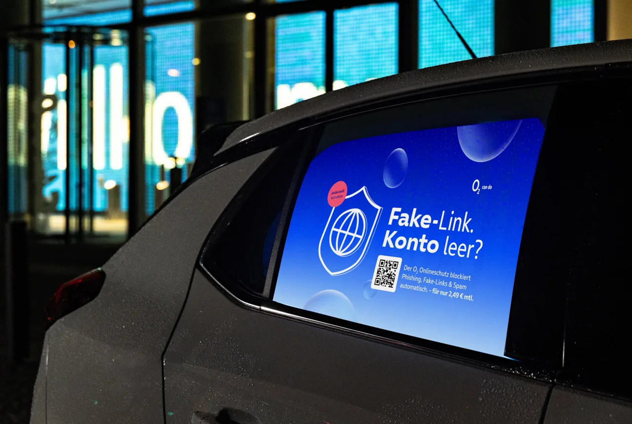 o2-Kampagnenmotiv Fake-Link, Konto leer? auf einem Bildschirm hinter einer Autoscheibe
