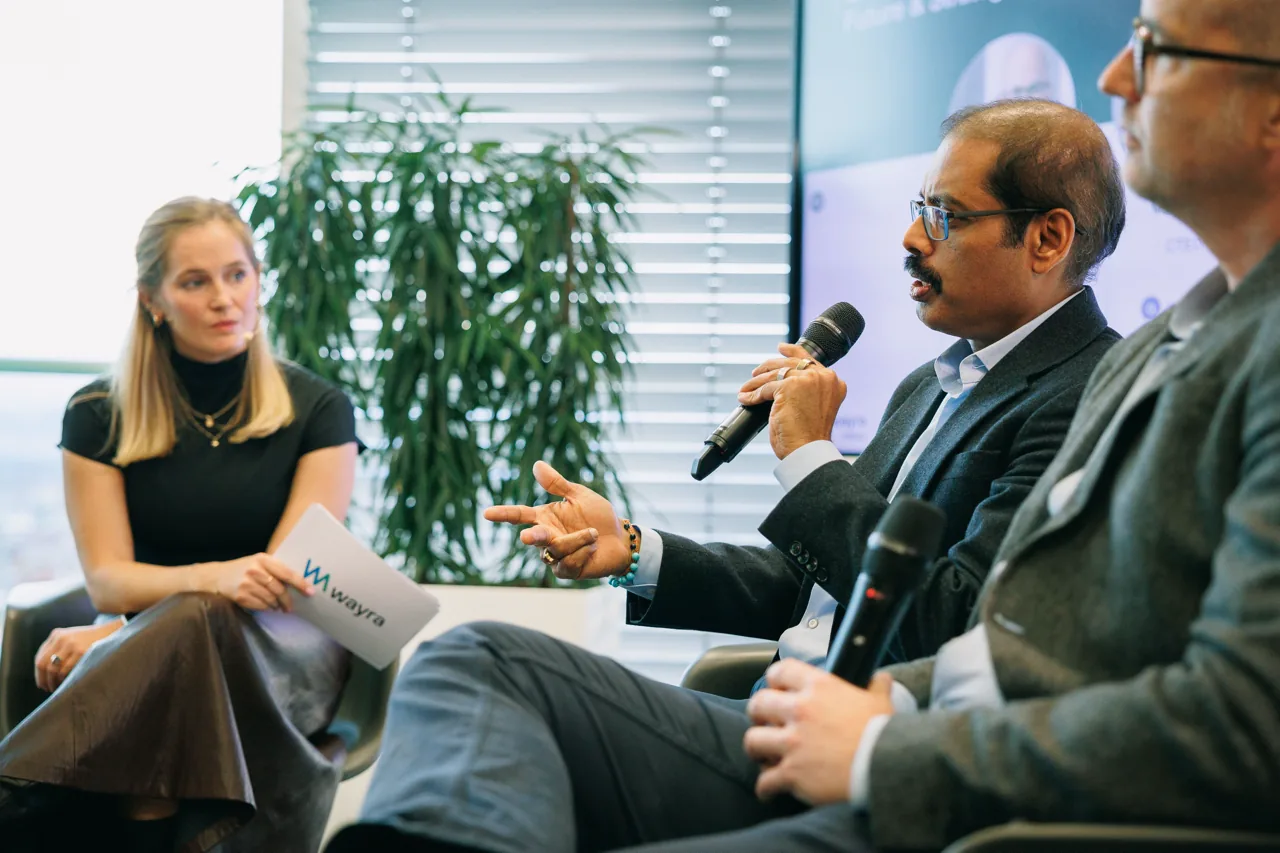 Panel-Diskussion: Speaker mit Mikrofon und Wayra-Unterlagen