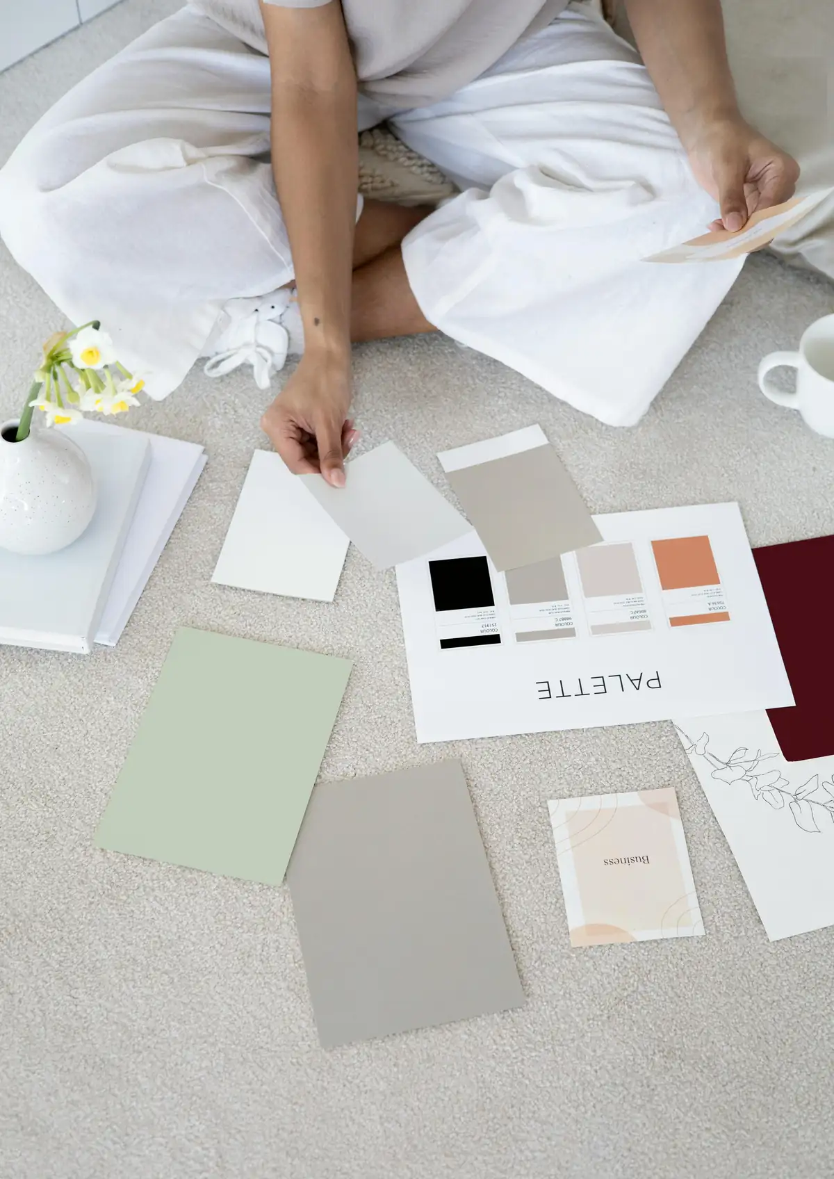 Designer sitting on the floor arranging colour swatches and material samples for an early design thinking prototype
