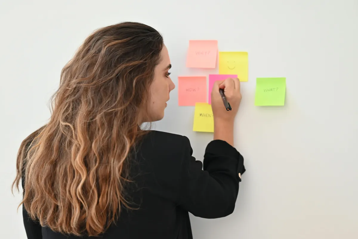 Woman arranging colourful sticky notes on a wall to map roles in a matrix organization