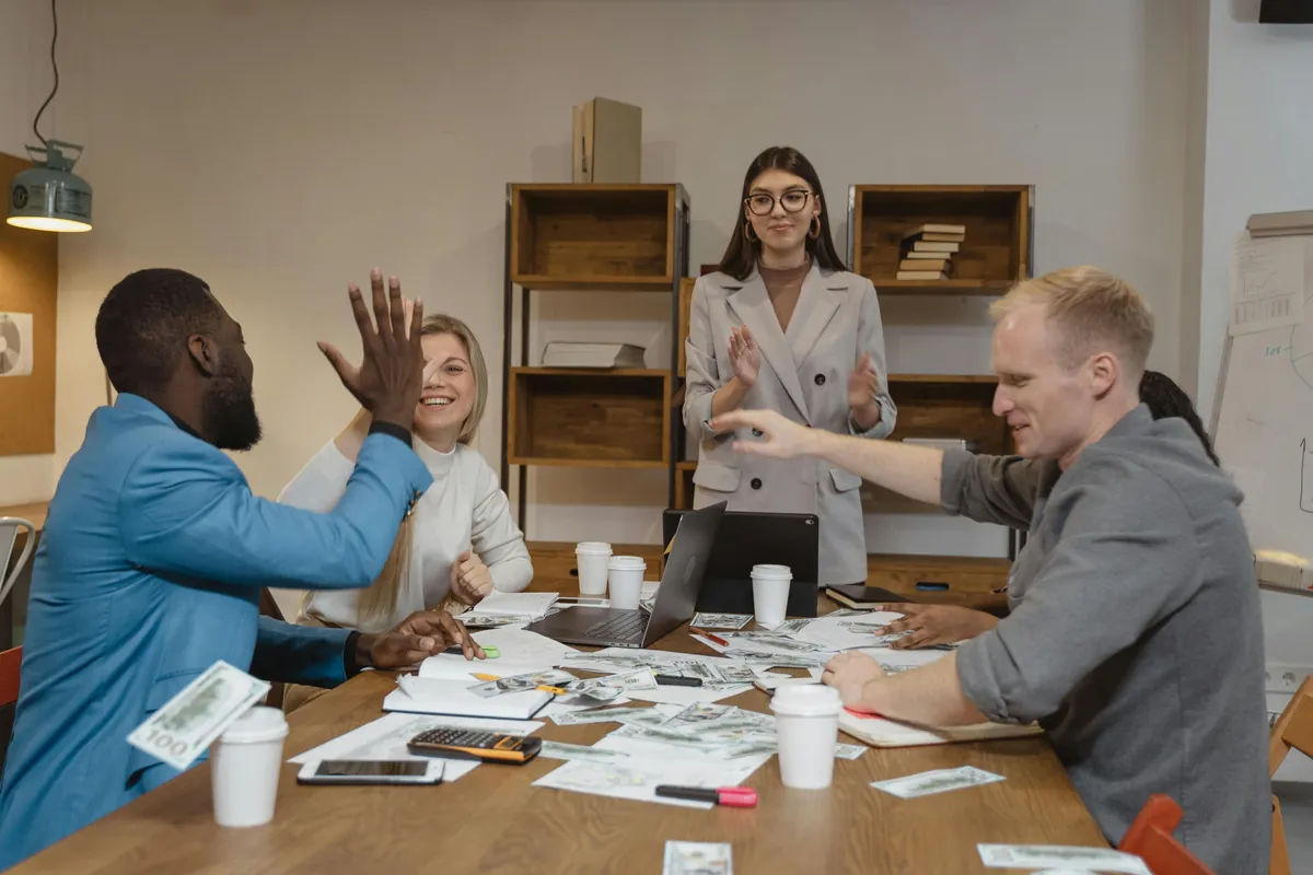 Team celebrating with a high five at a meeting table, living a shared corporate philosophy and culture