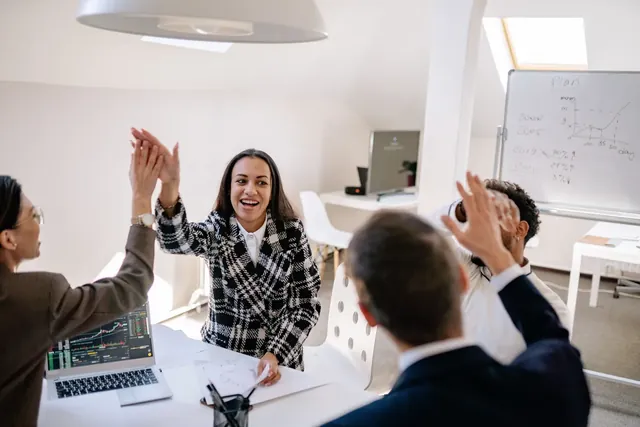 Startup-Team feiert im Büro einen gemeinsamen Erfolg mit High Five