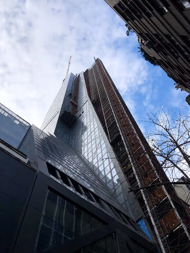 Vue de bas en haut sur un gratte-ciel en construction avec façade en verre.