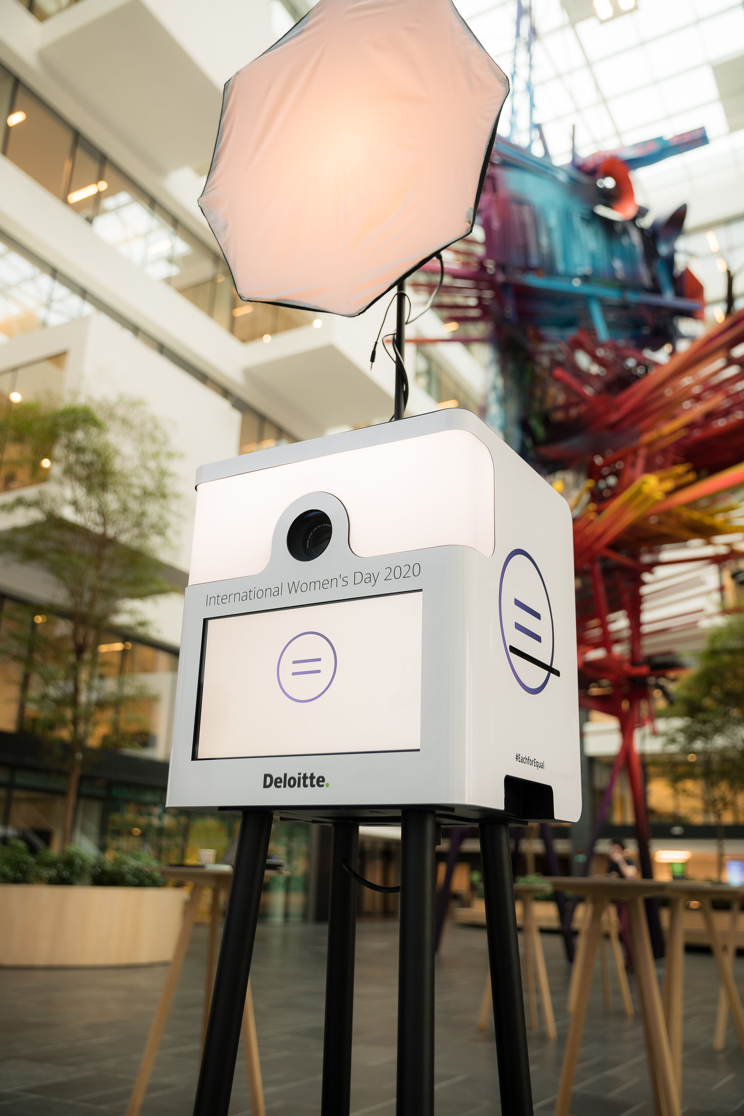 Fotohokje met verlicht softboxlicht en logo voor Internationale Vrouwendag 2020 van Deloitte binnen een modern gebouw.