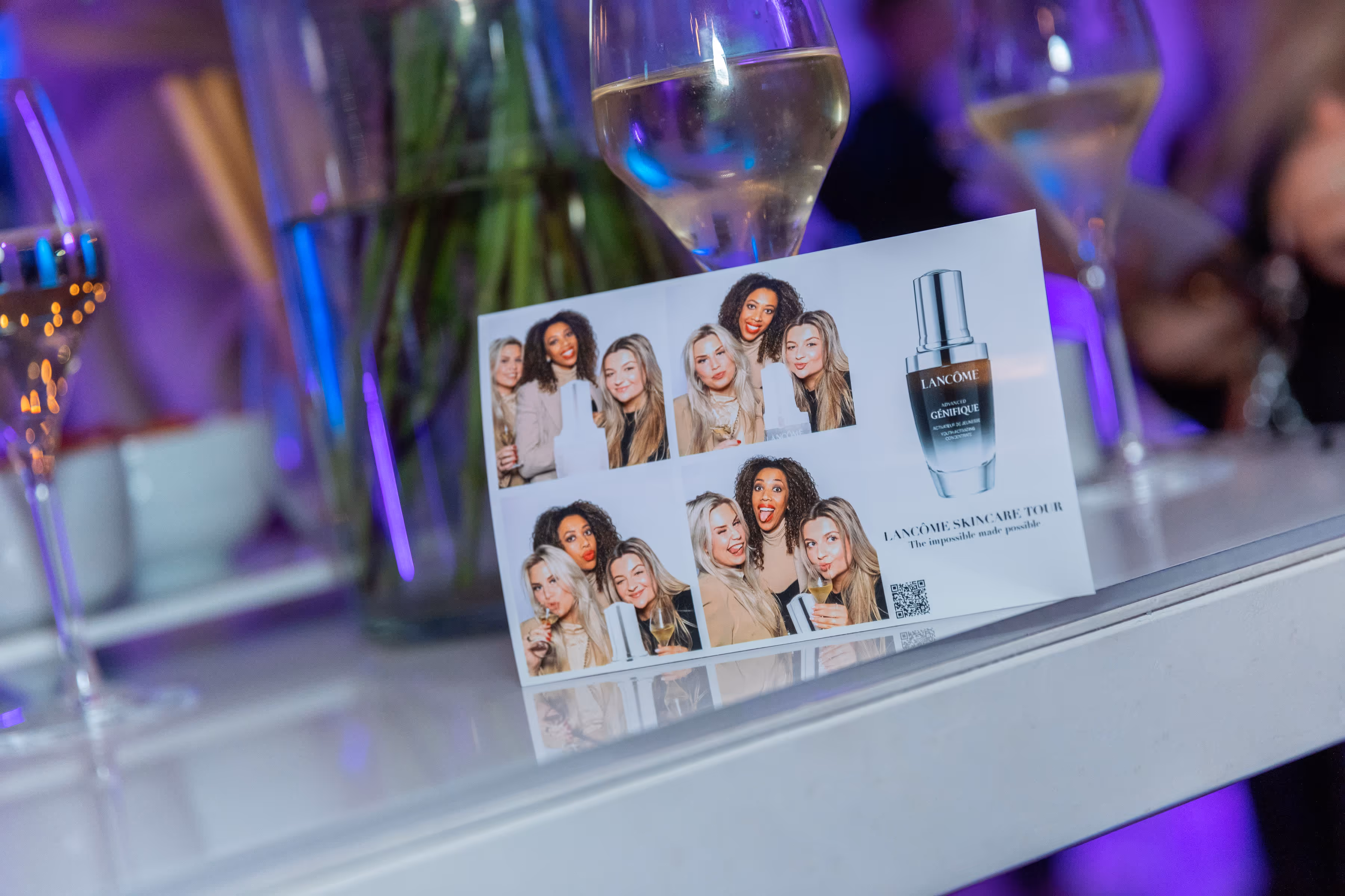 Fotos van vier lachende vrouwen op een Lancôme Skincare Tour kaart, met een afbeelding van een Génifique serumfles.