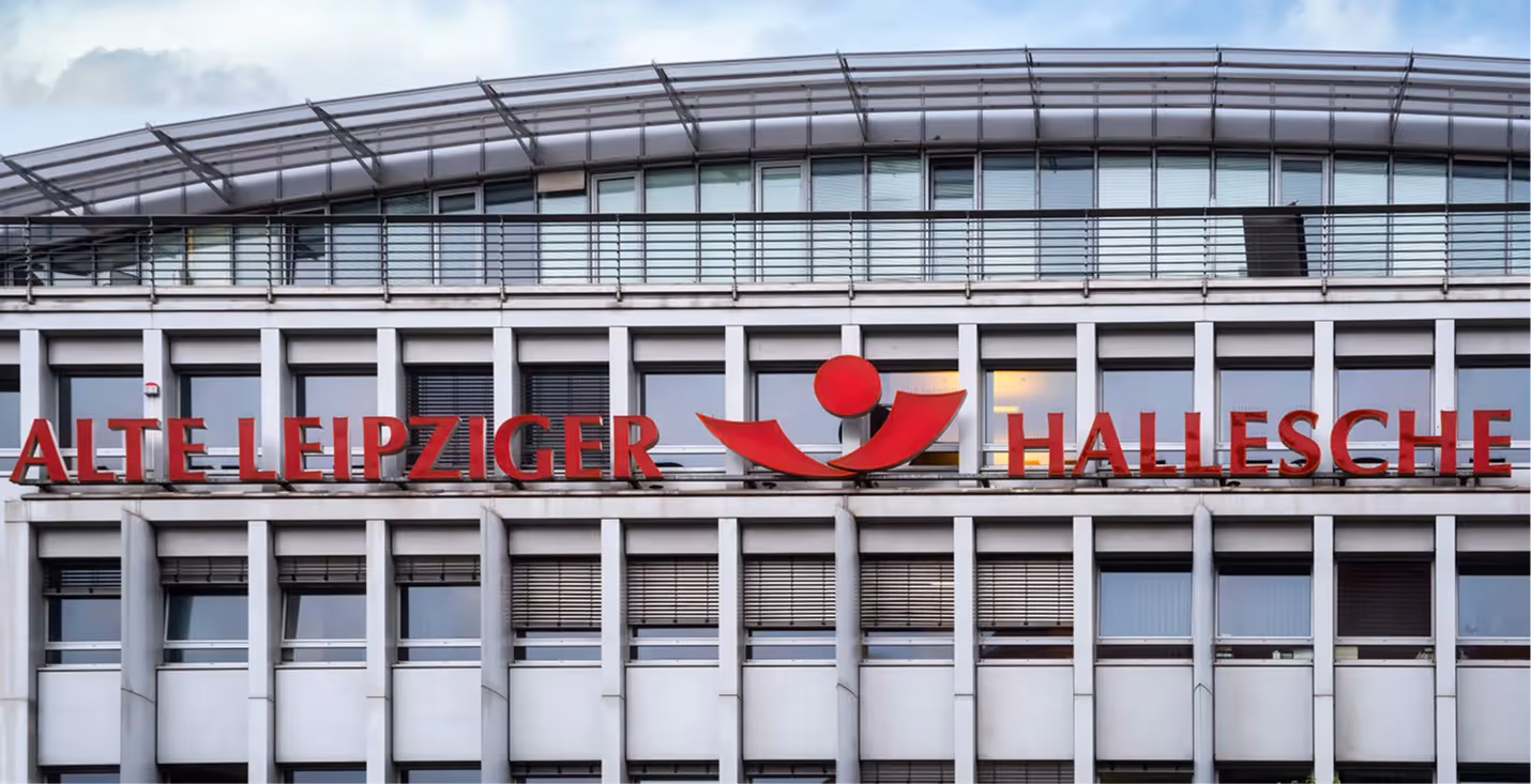 Rotes Logo und Schriftzug Alte Leipziger Hallesche an der Fassade eines modernen Bürogebäudes.