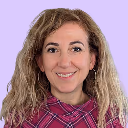 Porträt einer lächelnden Frau mit lockigem Haar und kariertem Oberteil vor lila Hintergrund.