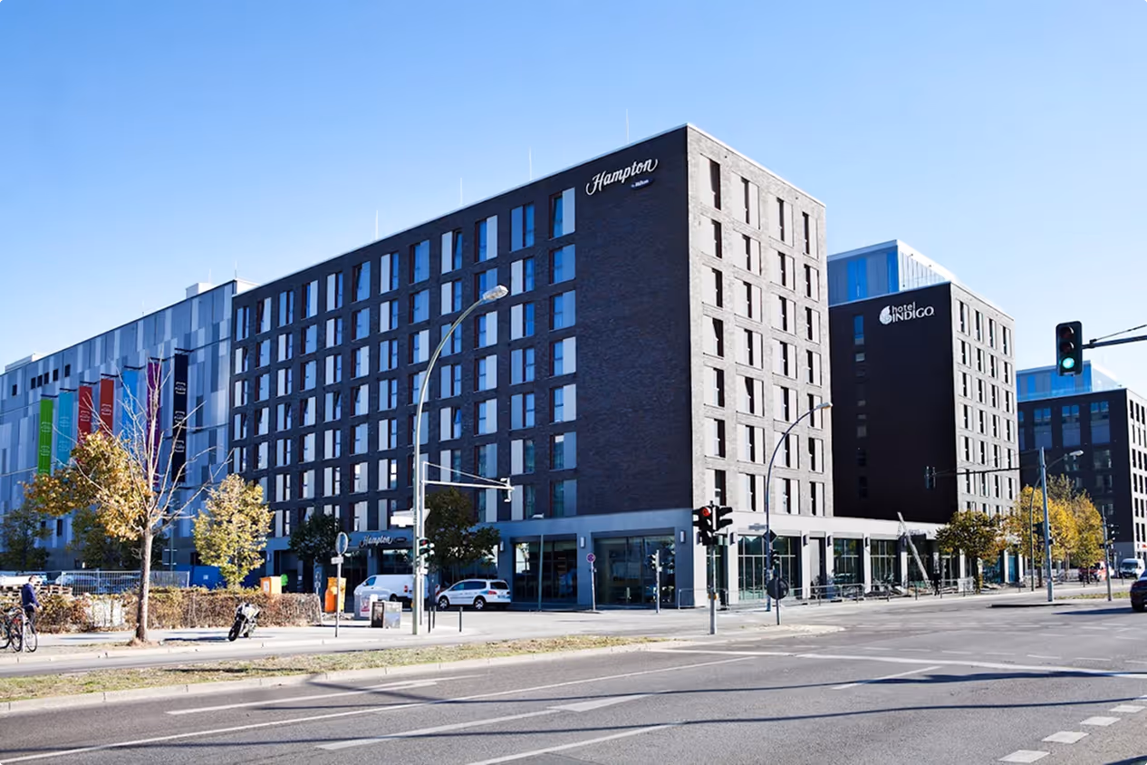 Moderne Gebäude mit Hampton- und Hotel Indigo-Schildern an einer Straßenkreuzung bei Sonnenschein.