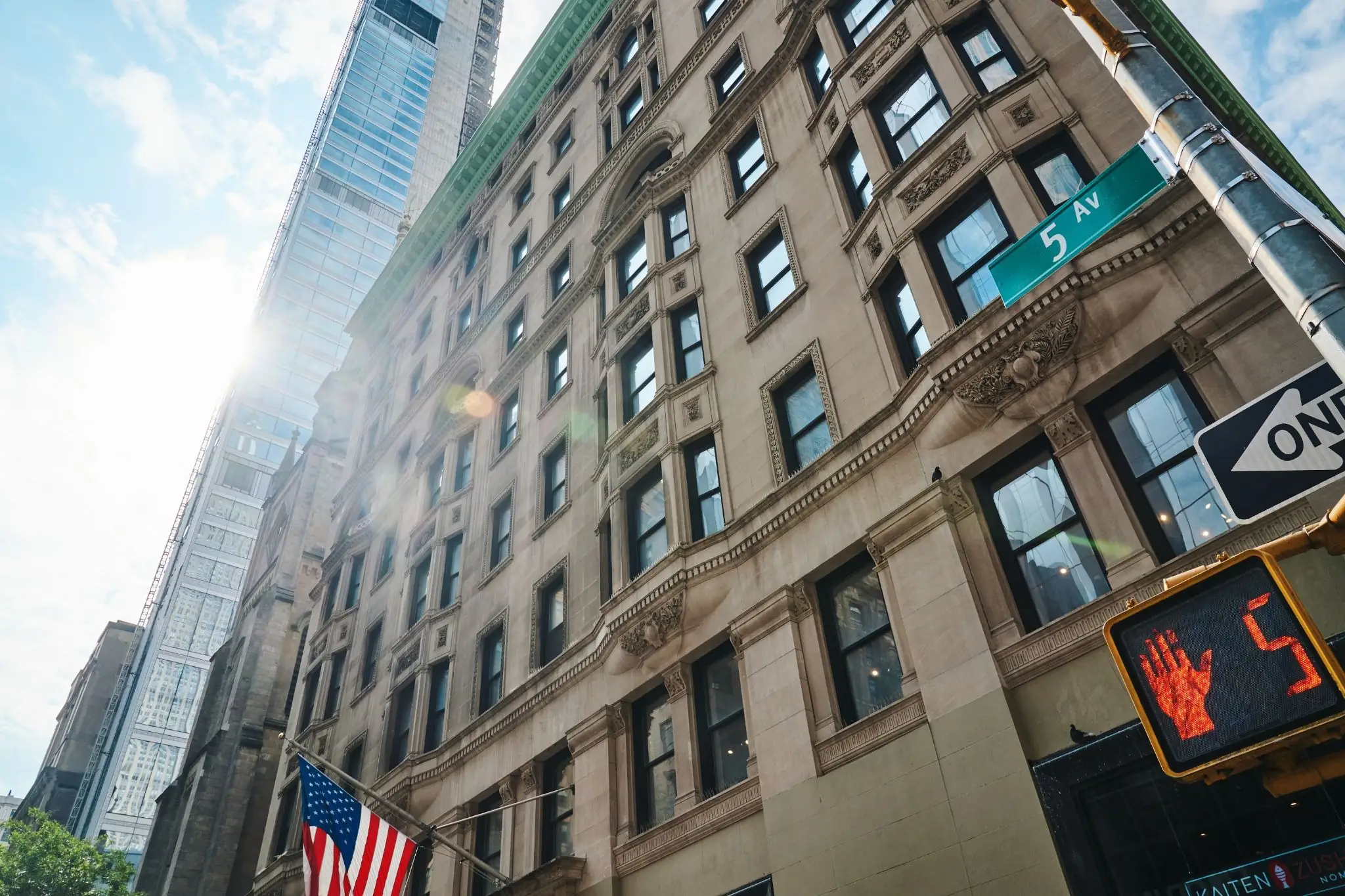     Buildings along Fifth Avenue in New York City with a street sign and pedestrian signal.
