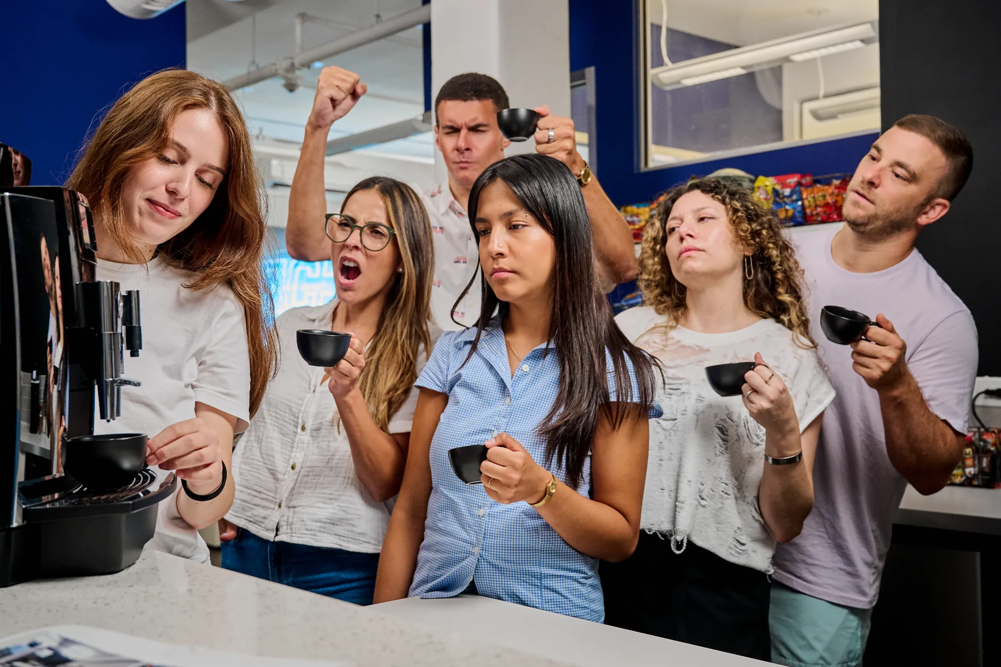 Team members gathered around a coffee machine in an office.