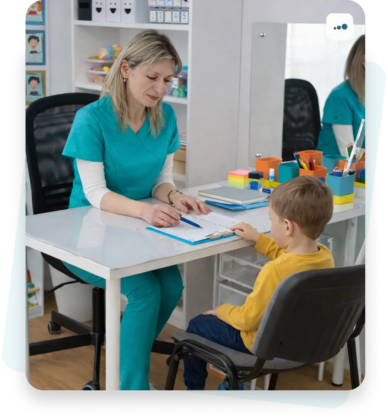 Logoped sedi za stolom u radu sa dečakom