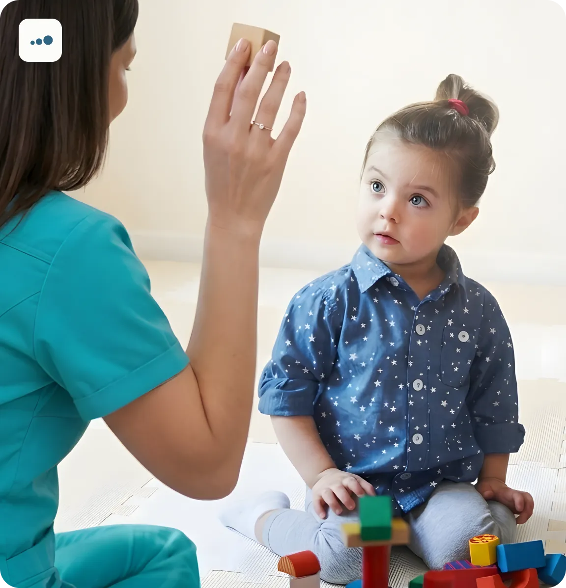 defektolg na podu pokazuje rukom devojčici koja gleda u pravcu ruke